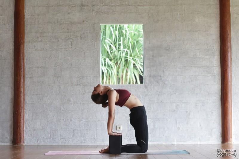 practicing camel pose with yoga blocks