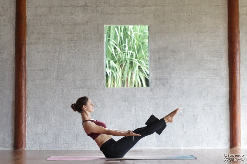 practicing boat pose with yoga block