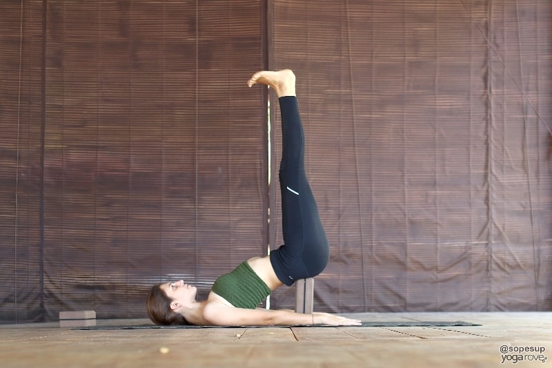 yogi practicing shoulderstand with yoga block restorative