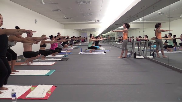 yoga instructor teaching Bikram yoga to many students