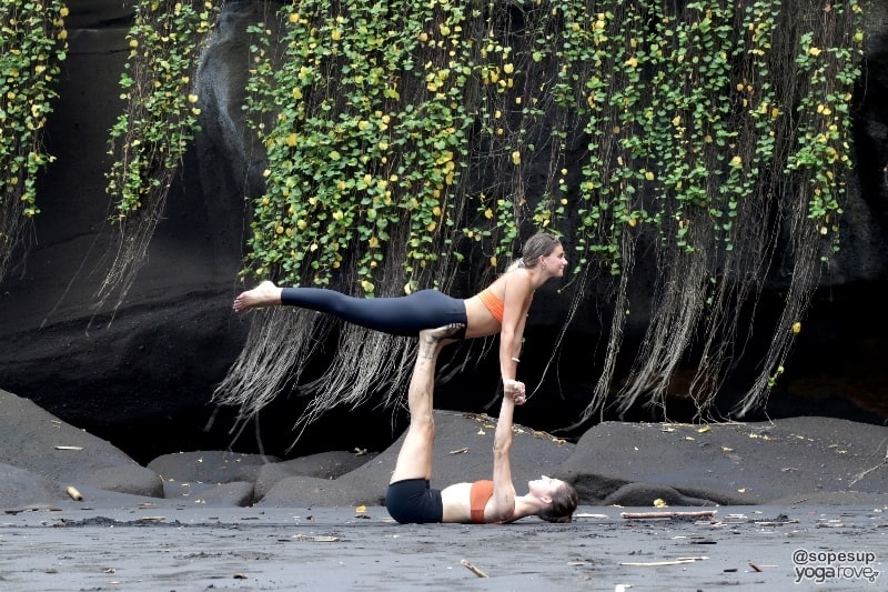 two yoga students practicing flying warrior partner yoga pose
