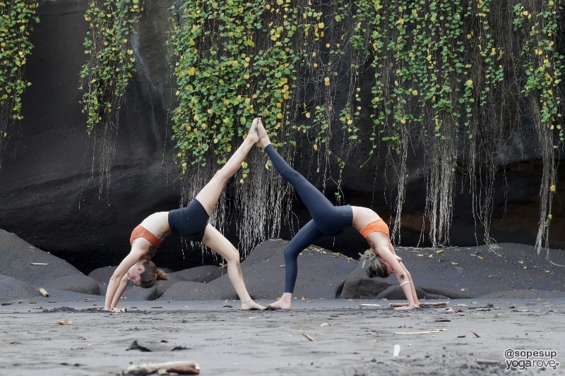 two yoga students practicing one legged wheel pose in partner yoga.