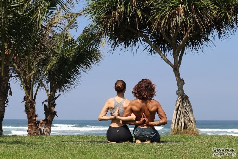 two yogis practicing partner yoga- reverse prayer