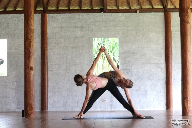 two yoga students practicing revolved triangle in partner yoga.