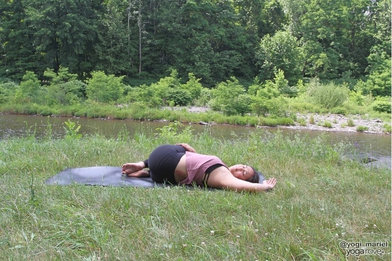 yogi practicing supine twist in sweaty yoga practice