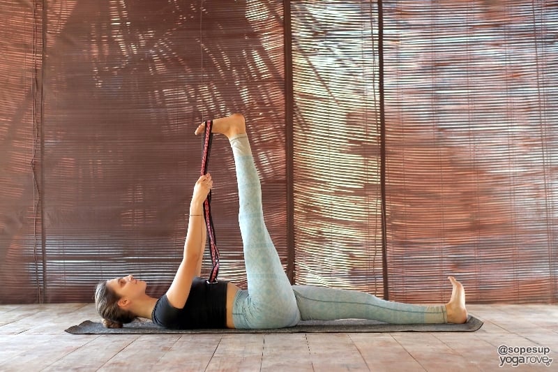 yogi practicing reclined big toe with yoga strap.