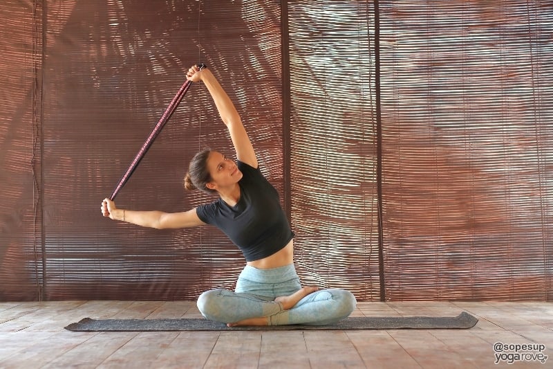 yogi practicing seated side stretch with yoga strap.