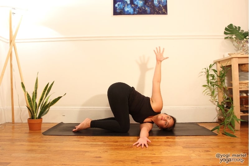 yogi practicing thread the needle arm variation with arm raised.