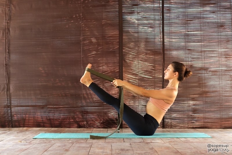 yogi practicing boat pose with strap.