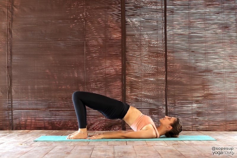 yoga student practicing bridge pose as counter to boat pose.