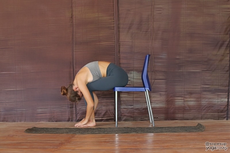 yogi practicing forward fold yoga pose in chair