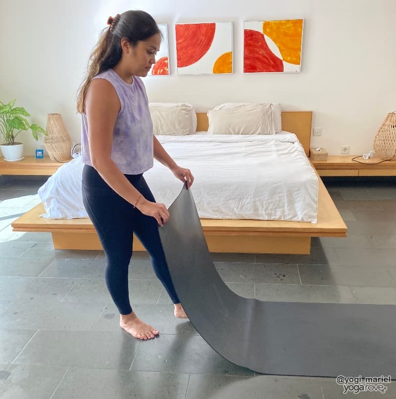 Yogi rolling out yoga mat at home